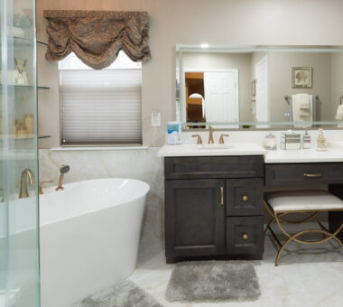 A luxurious bathroom featuring a freestanding bathtub, a glass-enclosed shower, a double vanity with dark cabinetry, and elegant gold fixtures. Luxury bathroom | Freestanding bathtub | Modern bathroom design | Spa-like bathroom | Elegant home interior